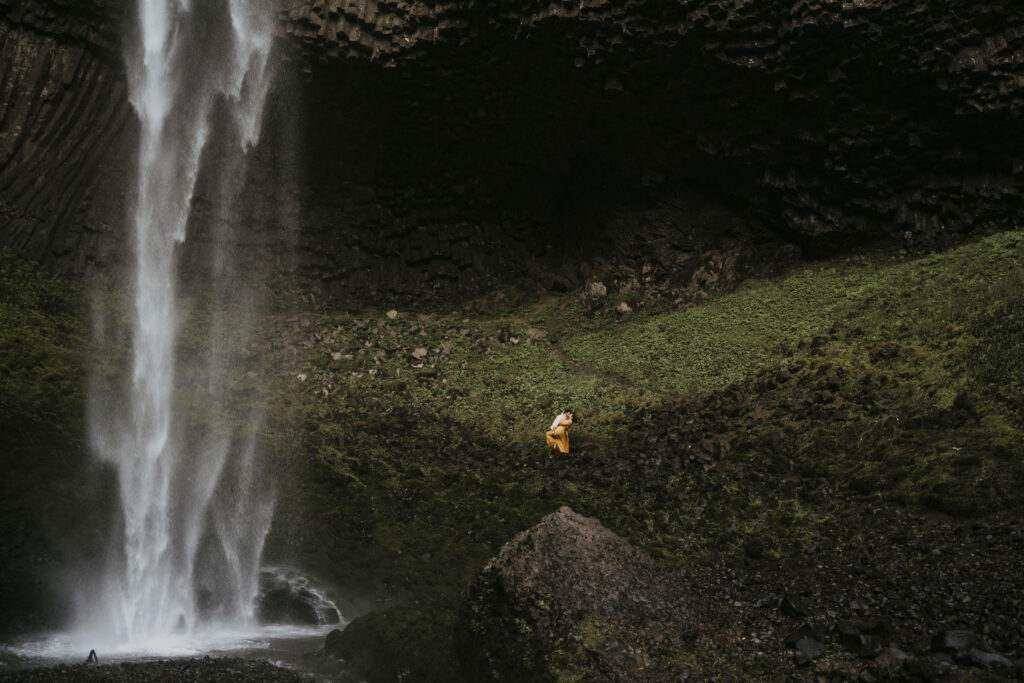 landscape photo of waterfall with a couple embracing