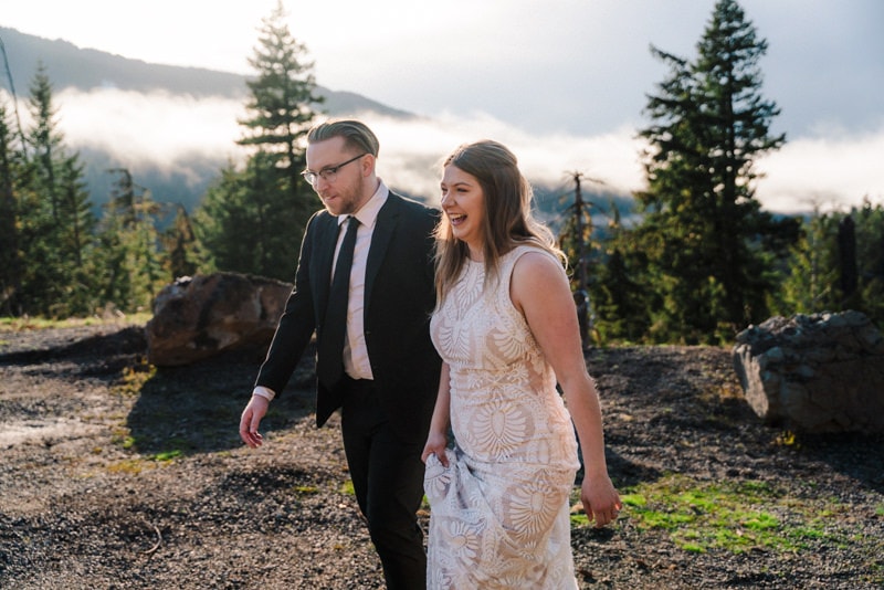 bride and groom walk in front of mountains smiling