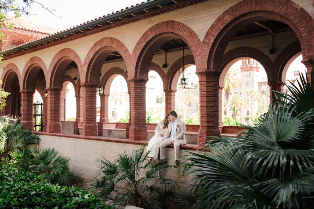 St. Augustine elopement photographer takes photo in Flagler college of couple sitting in an arch