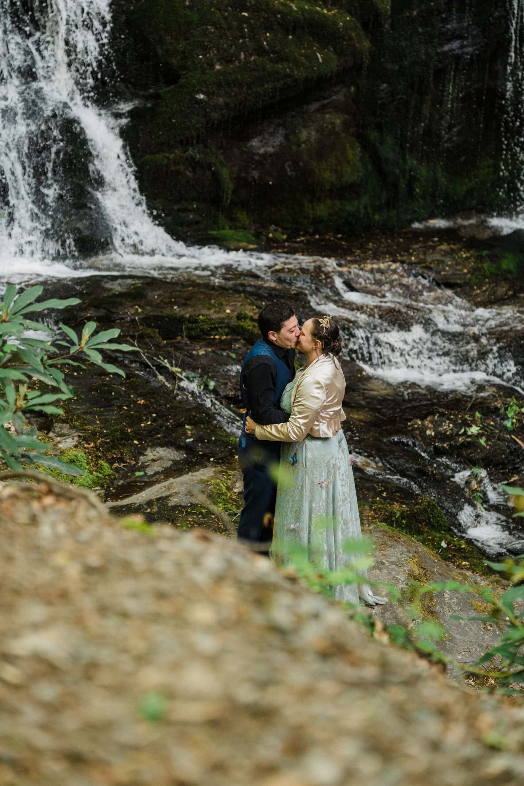 couple exchanging private vows in front of a waterfall during their blue ridge parkway elopement day