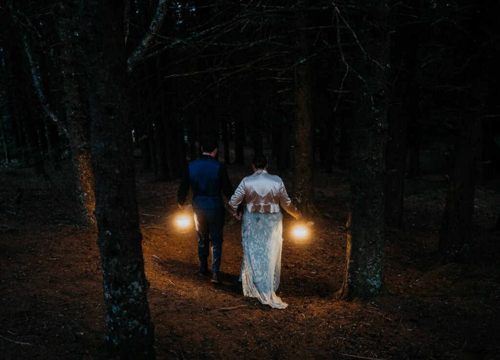 elopement couple roaming around a dark forest with lanterns during their blue ridge parkway elopement