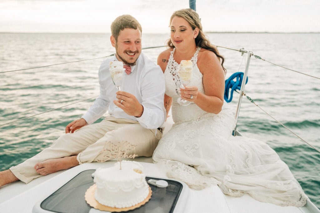 elopement couple eating cake on a sailboat during their florida sailboat elopement day