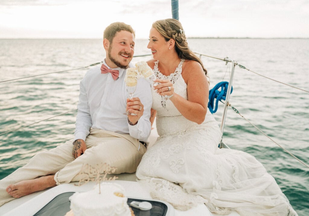 elopement couple eating cake on a sailboat during their florida sailboat elopement day