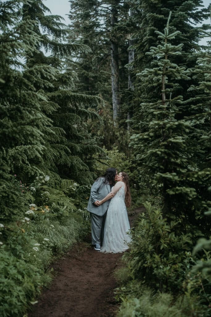 elopement couple hugging surrounded by lush evergreens